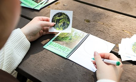 A person holding a sticker and writing in the Conservation Area Passport 